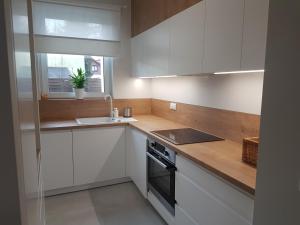 a kitchen with white cabinets and a sink and a window at Apartament Jasińskiego z ogrodem in Piaseczno