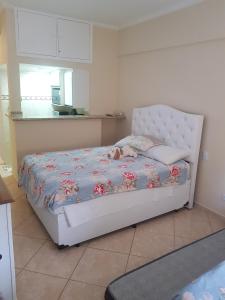 a bedroom with a white bed with flowers on it at Flat Hotel Cavalinho Branco in Águas de Lindóia