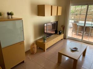 salon z telewizorem z płaskim ekranem i stołem w obiekcie Playa Burriana Rubasol Nerja w mieście Nerja