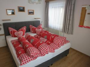 un montón de almohadas rojas en un sofá en una habitación en Ferienwohnung Eller, en Telfes im Stubai