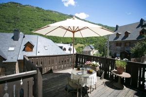 un patio con una mesa y una sombrilla en una terraza en Casa Rural Pico Russell, en Les Bordes