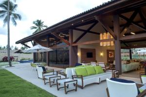 een patio met stoelen en tafels en een parasol bij Novo Bangalô no Malawi Beach House com Premium Service in Porto De Galinhas