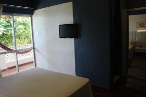 - une chambre avec un lit et une télévision murale dans l'établissement Hotel Icaraí, à Itaparica Town