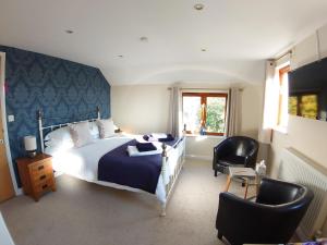 a bedroom with a large bed and two chairs at Oak Lodge B&B in Bude