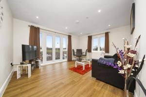 uma sala de estar com um sofá preto e uma televisão de ecrã plano em London Heathrow Living Serviced Apartments by Ferndale em Stanwell