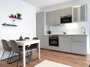 een witte keuken met een witte tafel en stoelen bij White Inn - Ferienwohnung mit Terrasse in Mürzzuschlag