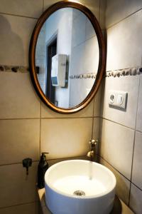 La salle de bains est pourvue d'un lavabo blanc et d'un miroir. dans l'établissement Gîte rural Les petites têtes, à Leuze-en-Hainaut