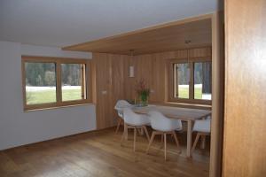 a dining room with a table and chairs and windows at kirchdorf 300 in Bizau