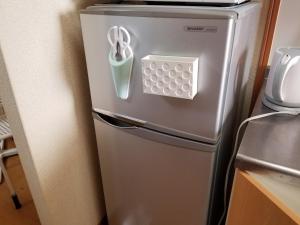 einen silbernen Kühlschrank mit einer Schere darauf in der Unterkunft Takaraboshi room 101 Sannomiya10min in Kōbe