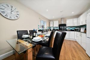 cocina con mesa de comedor y reloj en la pared en London Heathrow Living Serviced Apartments by Ferndale, en Stanwell