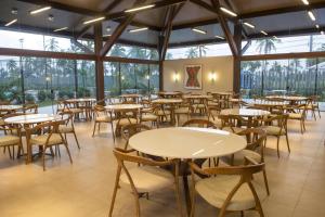 - une salle à manger avec des tables, des chaises et des fenêtres dans l'établissement Novo Bangalô no Malawi Beach House com Premium Service, à Porto de Galinhas