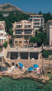 a large building with chairs and umbrellas in the water at Vila Fortuna in Sutomore