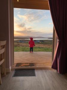 uma criança pequena parada do lado de fora de uma porta em Hebridean Holiday Cabins em Breasclete
