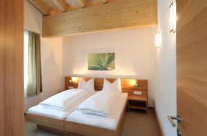 um quarto com uma cama com almofadas brancas em Apart Ladner em Sankt Anton am Arlberg