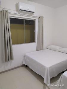 - une chambre blanche avec un lit et une fenêtre dans l'établissement Condomínio Praia dos Corais 1, à Coroa Vermelha