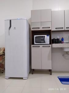 uma cozinha com um frigorífico branco e um micro-ondas em Condomínio Praia dos Corais 1 em Coroa Vermelha