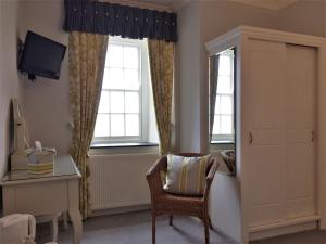 een kamer met een stoel, een bureau en 2 ramen bij Tregiffian Farm B&B in Penzance