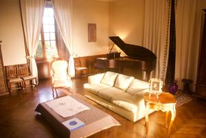 a living room with a white couch and a piano at Chateau De Piedouault in Jallais