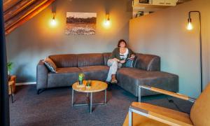 una mujer sentada en un sofá en una sala de estar en Hoeve Springendal en Ootmarsum