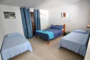 two beds in a room with blue curtains at Villa Bali Maresias in Maresias