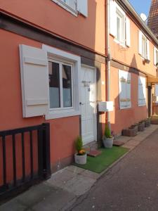 una casa con una puerta blanca y macetas en una calle en LE PETIT FLECK en Haguenau