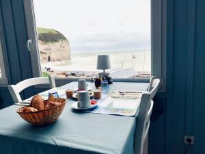 a blue table with a basket of bread and a view of the beach at Hôtel La Sirène in Yport