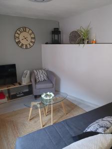 ein Wohnzimmer mit einem Tisch, einem Stuhl und einer Uhr in der Unterkunft LE PETIT FLECK in Haguenau