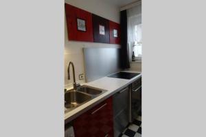 a kitchen with red cabinets and a sink at Schöne, ruhige Wohnung in Berlin-Steglitz in Berlin