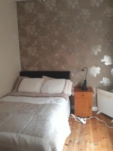 1 dormitorio con 1 cama y una pared con flores en Apartment in the Heart of Kerry en Knockeen Cross Roads