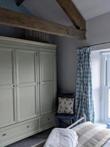 a bedroom with a bed and a cabinet and a window at Fell View, Slaggyford in Brampton