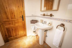 a bathroom with a white sink and a wooden door at Apartamentos Pumarin in Santa Marina +37 photos