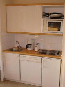 a kitchen with white cabinets and a sink and a microwave at Résidence Marie Galante Locmaria avec piscine in Locmaria