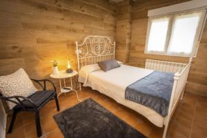 a bedroom with a bed and a chair and a window at Apartamentos Pumarin in Santa Marina