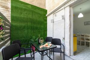 a patio with a table and chairs and a green wall at Litsa's Suite in Heraklio