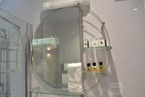 a bathroom with a mirror and a towel rack at Lauriston & Lawton Court Hotel in Llandudno