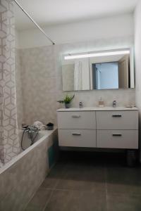 een badkamer met een witte wastafel en een spiegel bij Très bel appartement avec grande terrasse in Porto-Vecchio