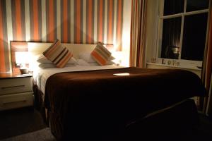 a bedroom with a bed with pillows and a window at Lauriston & Lawton Court Hotel in Llandudno