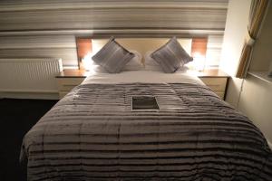 a bedroom with a large bed with a book on it at Lauriston & Lawton Court Hotel in Llandudno