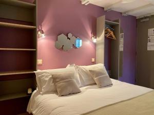 a bedroom with a white bed with purple walls at Hôtel des Bains in Figeac