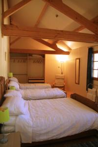 Habitación con 4 camas con sábanas blancas. en Loire Escapes, en Berrie