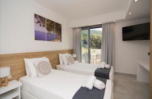 ein Hotelzimmer mit zwei Betten und einem Fernseher in der Unterkunft Olivista Hotel in Perdika + 25 Fotos