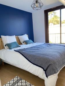 een slaapkamer met een groot bed met een blauwe muur bij Appartement cosy village de L'Herbe in Lège-Cap-Ferret