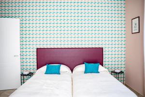 1 dormitorio con 1 cama con 2 almohadas azules en Appartamenti Rocca - CAV La Casa di Rosa, en Monforte dʼAlba