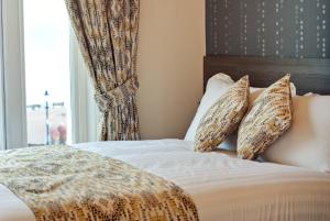 a bedroom with a bed with pillows and a window at Lauriston & Lawton Court Hotel in Llandudno