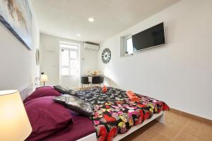 een slaapkamer met een bed en een tv aan de muur bij Studio apartment Bašćan in Trogir