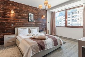a bedroom with a wooden accent wall and a bed at A50 Cape Town Penthouse - Silver Mountain in Poiana Brasov