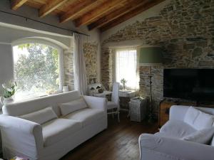a living room with white furniture and a stone wall at Casale Maria Mafalda in Pieve di Teco