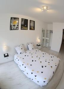 a bedroom with a large white bed with gold triangles at Sympathique logement en centre ville in Verdun