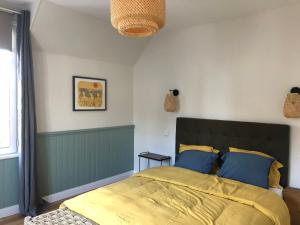a bedroom with a bed with yellow sheets and blue pillows at Historic "Touquettoise" villa, located in heart of the village, 100m from the beach, with sunny terrace and private garden in Le Touquet-Paris-Plage