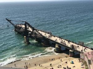 um cais na praia com pessoas a caminhar sobre ele em Departamento primera vista al mar em Viña del Mar